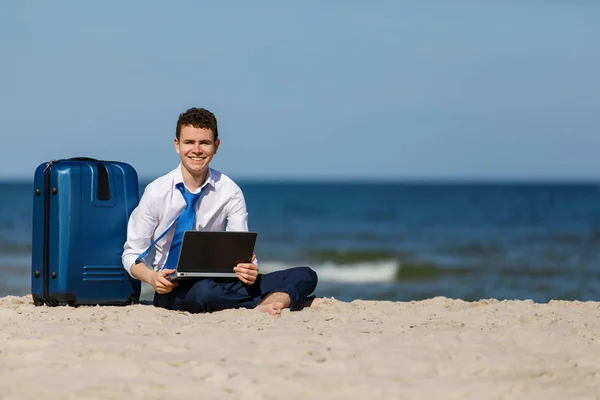 近くのスーツを着た男が海辺のラップトップコンピュータで働いている — ストック写真