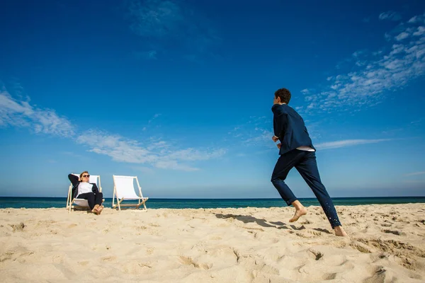 Woman Man Suits Sandy Beach Man Having Fun Jumping Seaside — Stockfoto