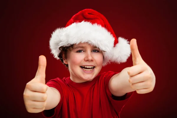 Kırmızı Arka Planda Noel Baba Şapkalı Yakışıklı Çocuk — Stok fotoğraf