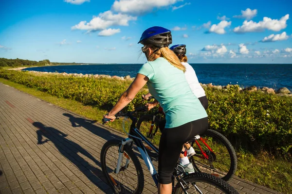 Två Medelålders Kvinnor Rida Cyklar Vid Havet — Stockfoto
