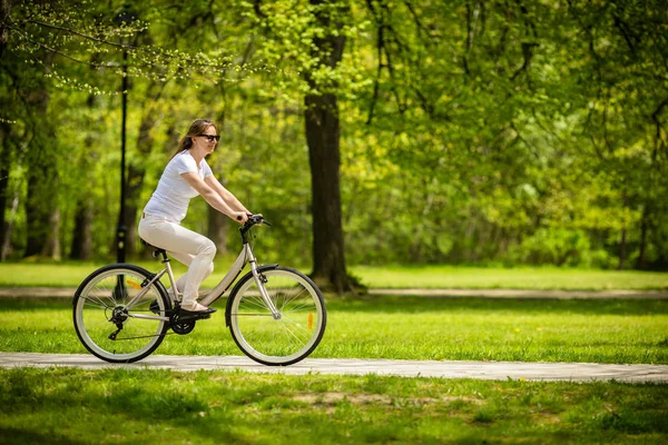 Bahar Parkında Bisiklet Süren Beyaz Elbiseli Bir Kadın — Stok fotoğraf