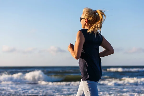 アクティブな女性が海でジョギング — ストック写真