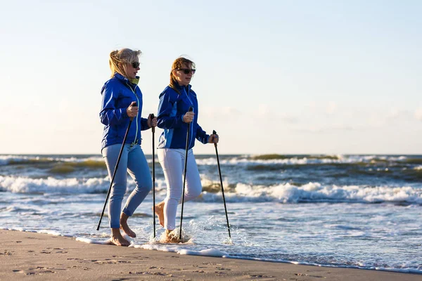 海岸沿いの観光用の棒で歩く2人の中年女性 ノルディックウォーキング — ストック写真