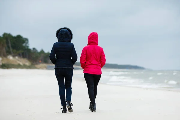 海で冬のビーチを歩く二人の女性 — ストック写真