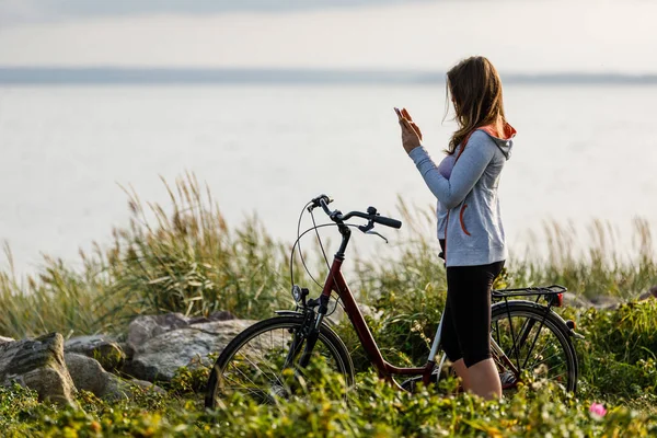 海辺で自転車に乗ると長髪の若い女性が休んでいる — ストック写真