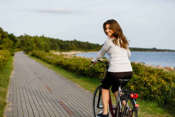 海辺で長髪自転車に乗る若い女性 — ストック写真