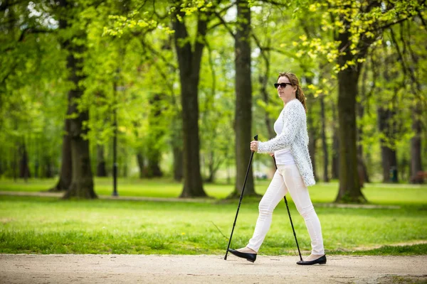 Mulher Roupas Casuais Brancas Andando Parque Primaveril Usando Paus Turísticos — Fotografia de Stock