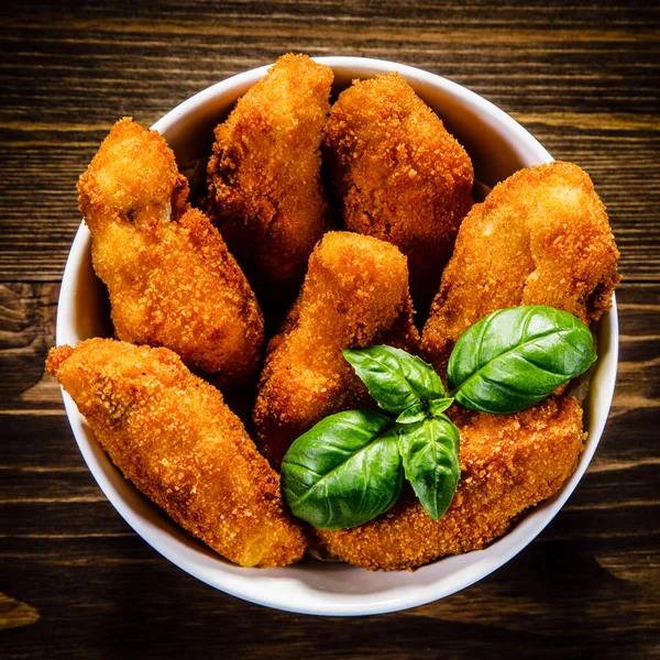 Breaded chicken wings in bowl with basil