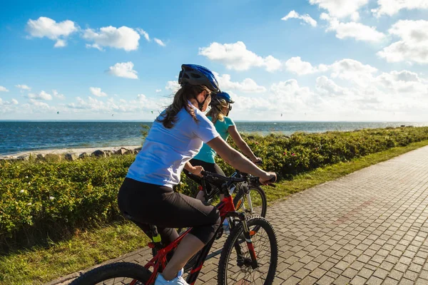 Två Aktiva Kvinnor Sportkläder Ridning Cyklar Stranden Sommaren — Stockfoto