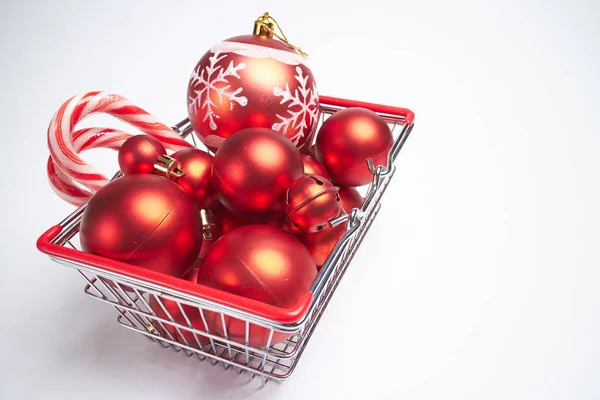 Christmas balls with candies in shopping cart — Stock Photo, Image