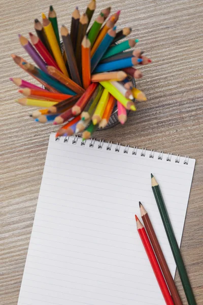 Бумага с цветными карандашами на деревянном столе — стоковое фото