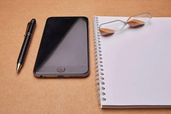 Современный смартфон с блокнотом на офисном столе , — стоковое фото
