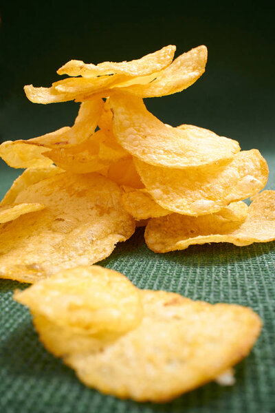 хрустящие картофельные чипсы на зеленой скатерти
 