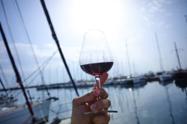 Erkek el ile yat arka plan üzerinde kırmızı şarap tutarak 