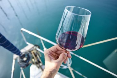 Erkek el ile yat arka plan üzerinde kırmızı şarap tutarak 