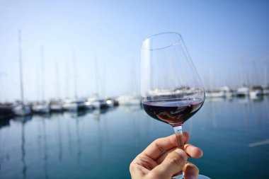 Erkek el ile yat arka plan üzerinde kırmızı şarap tutarak 