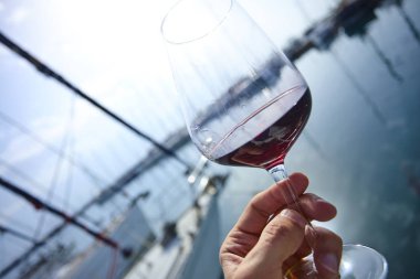 Erkek el ile yat arka plan üzerinde kırmızı şarap tutarak 