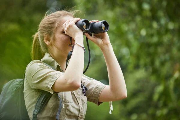 Frau mit Rucksack blickt auf Fernglas — Stockfoto