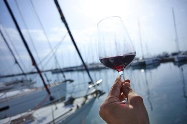 Erkek el ile yat arka plan üzerinde kırmızı şarap tutarak 