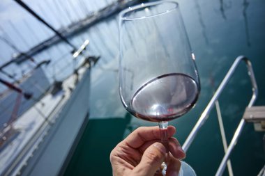 Erkek el ile yat arka plan üzerinde kırmızı şarap tutarak 