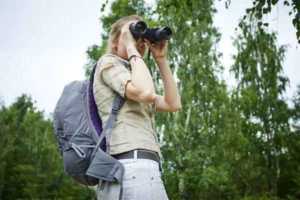 Kvinna med ryggsäck tittar på kikare — Stockfoto