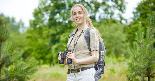 Frau mit Rucksack blickt auf Fernglas — Stockfoto