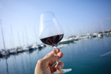 Erkek el ile yat arka plan üzerinde kırmızı şarap tutarak 