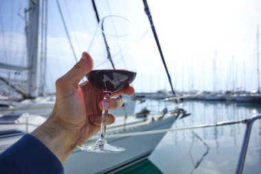 Erkek el ile yat arka plan üzerinde kırmızı şarap tutarak 