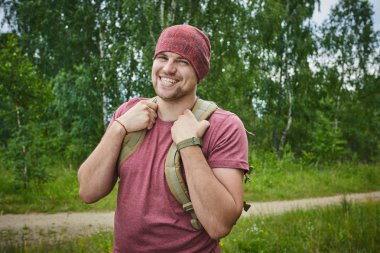 güneşli bir gün, çayır üzerinde sırt çantası ile genç adam 