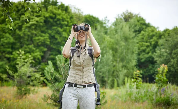 Kvinna med ryggsäck tittar på kikare — Stockfoto