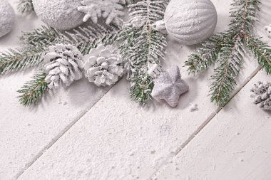 Masa arkasında süslemeleri olan karlı Noel ağacı dalları