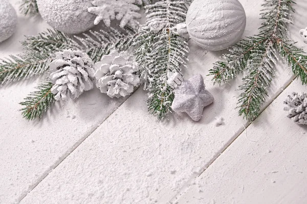 Masa arkasında süslemeleri olan karlı Noel ağacı dalları