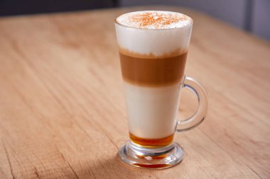 Ahşap zemin üzerinde cam şerbetli latte macchiato, yakın görüş.