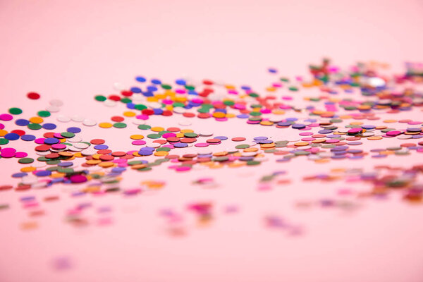 куча разноцветных конфетти на розовом фоне
