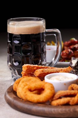 Ahşap kesme tahtasında meze ile servis edilen filtresiz bira pint, yakın çekim 