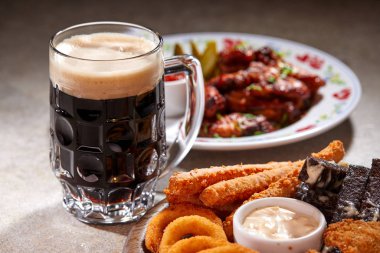 Ahşap kesme tahtasında meze ile servis edilen filtresiz bira pint, yakın çekim 