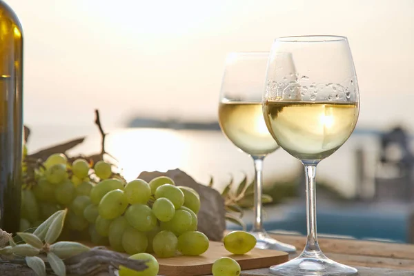 two glasses with wine and bottle during sunset time