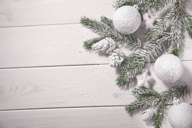 Karlı ağaç dalları ve ahşap arka planda süslemeleri olan Noel kartı