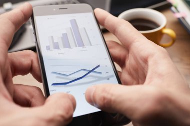 Erkek eller modern akıllı telefon kullanıyor. Ekranda grafik var. İş konsepti. 