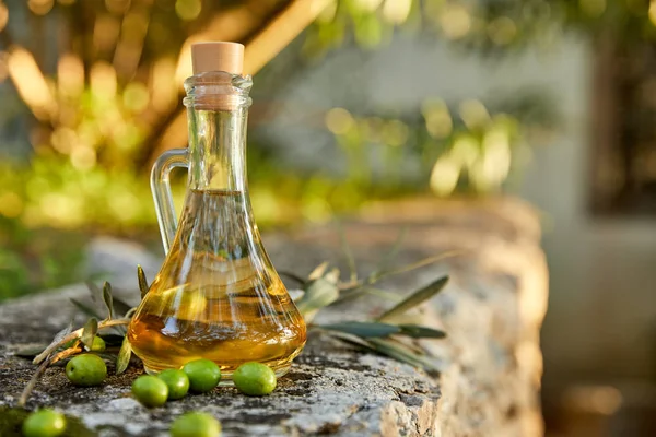 オリーブオイルと新鮮なオリーブのガラス瓶と屋外の葉 — ストック写真