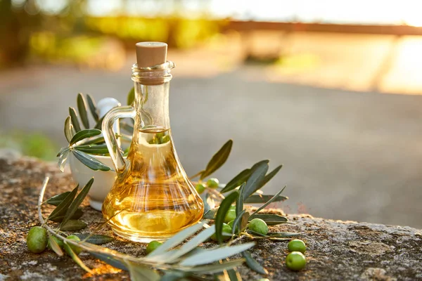 jug with olive oil and green olives on table