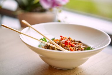 Kızarmış erişteli sobayı sığır eti ve çubukla karıştırın, yakından bakın.