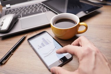 Erkek eli modern akıllı telefon kullanıyor. Ekranda grafik var. İş konsepti. 