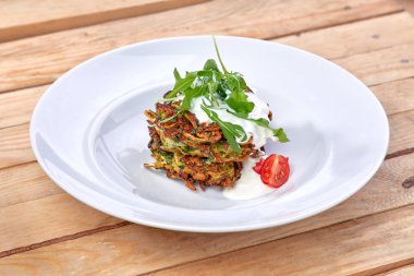 Ekşi kremalı kabak gözlemeleri ve beyaz tabakta bitkiler, yakın plan. 