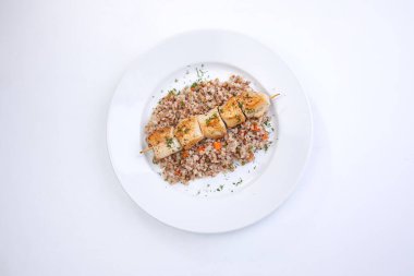 Beyaz tabakta karabuğdaylı tavuk kebabı, yakın görüş.