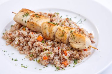 Beyaz tabakta karabuğdaylı tavuk kebabı, yakın görüş.