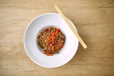 Kızarmış erişteli sobayı beyaz tabakta sığır etiyle karıştır, yakın görüş.