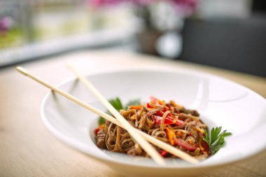 Kızarmış erişteli sobayı beyaz tabakta sığır etiyle karıştır, yakın görüş.