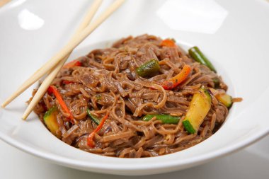 Kızarmış erişteli sobayı sığır eti ve çubukla karıştırın, yakından bakın.