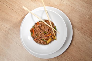 Kızarmış erişteli sobayı sığır eti ve çubukla karıştırın, yakından bakın.